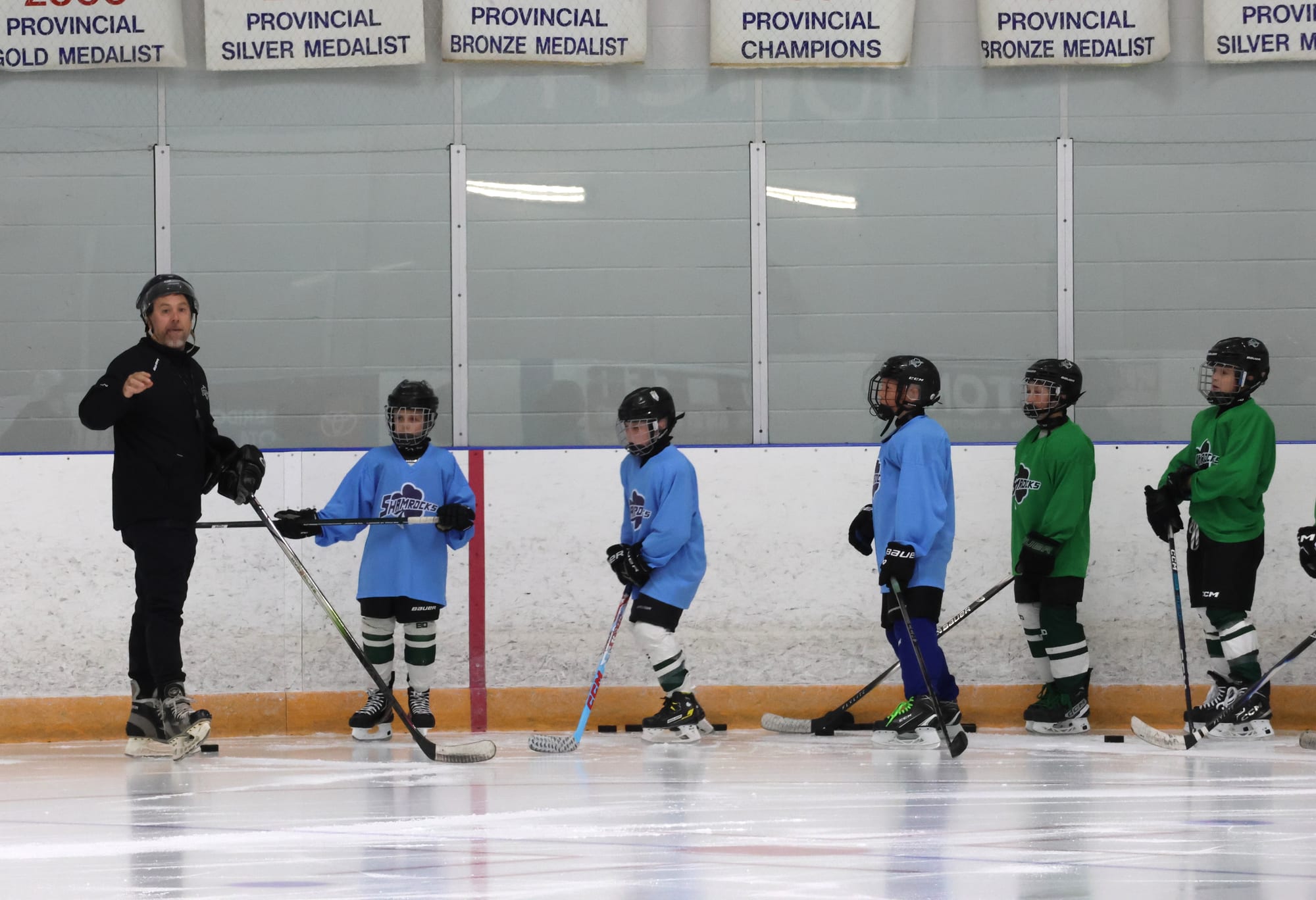 Jesse walking a line of players through a drill at the boards