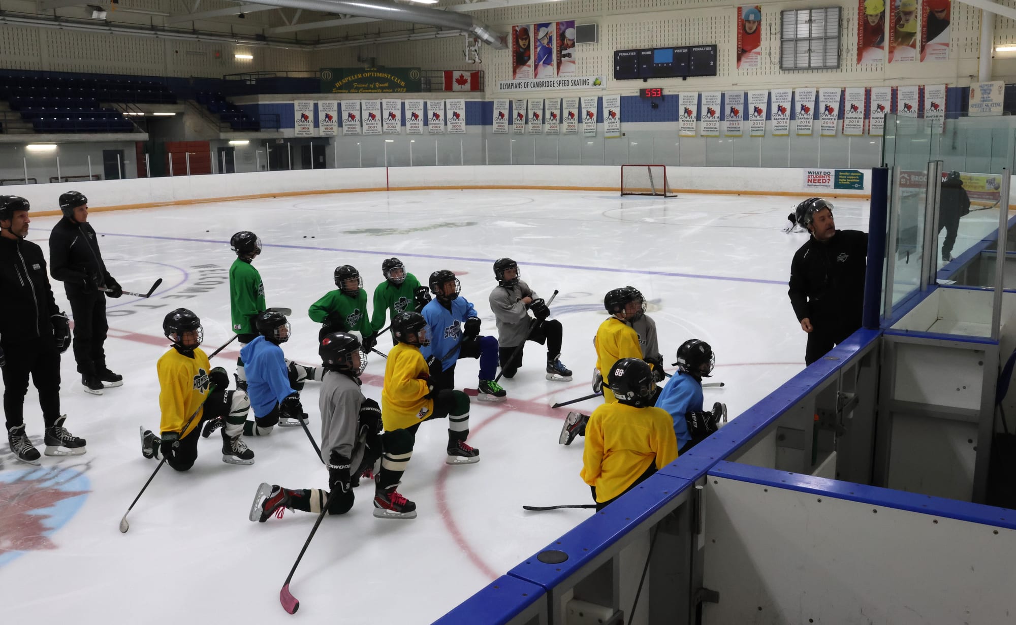 Jesse and two coaches running a practice with players gathered at the boards
